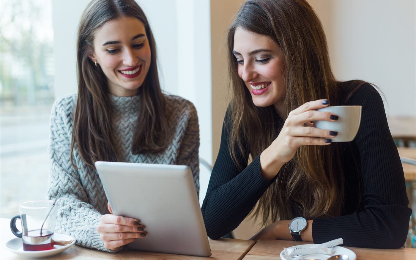 Two students smiling as they work together on a tablet