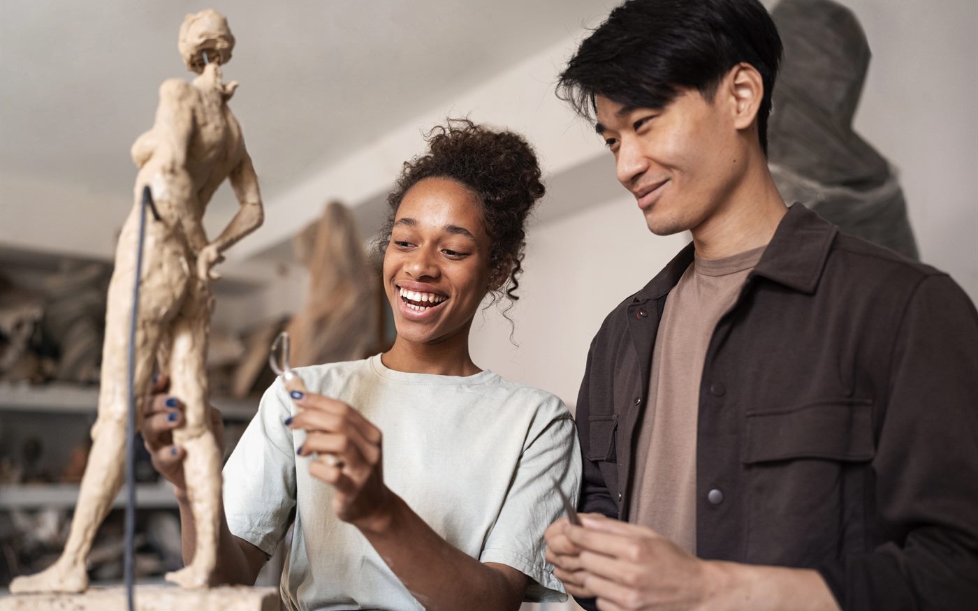 Two young people laughing together at a clay sculpting workshop